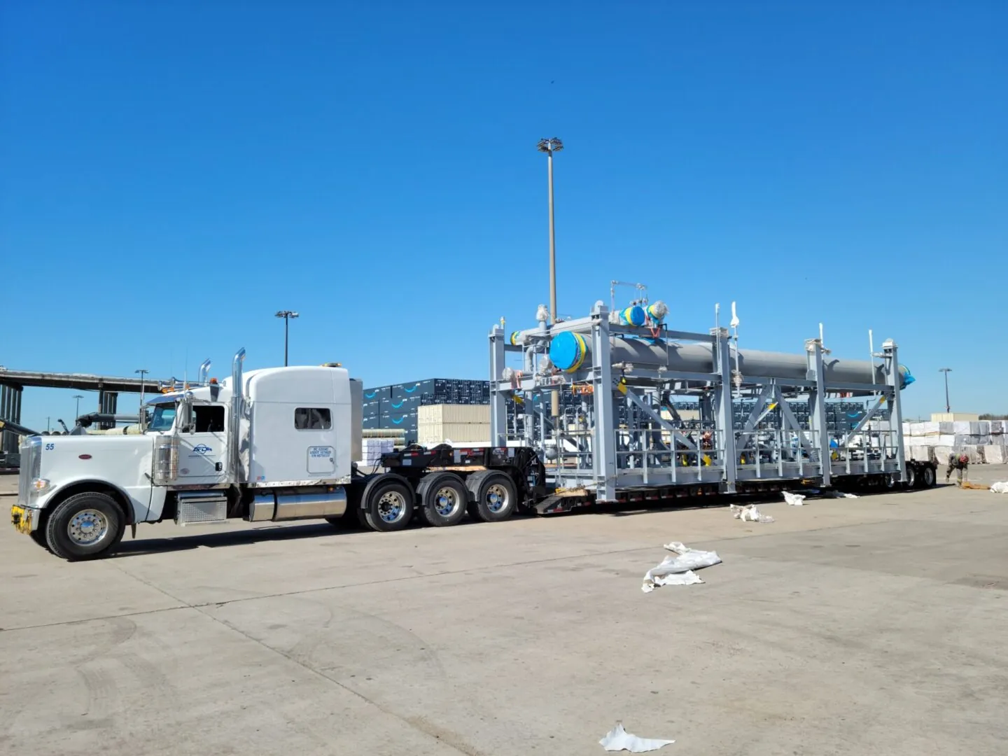 White semi truck hauling a large steel structure on a multi-axle trailer