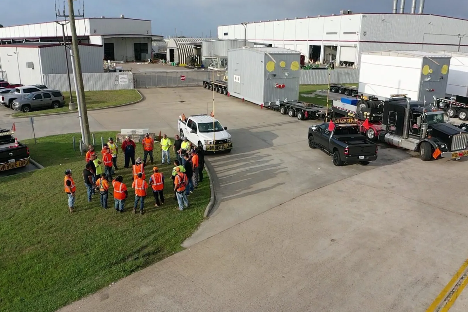 Construction crew briefing next to oversized trailers
