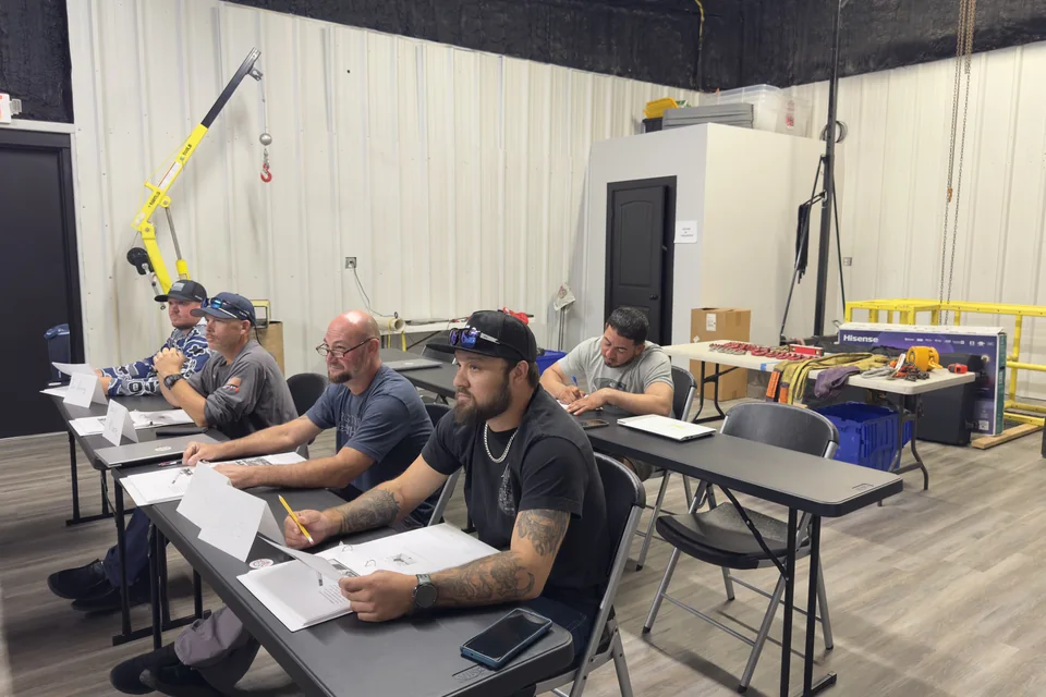 Team members attending a classroom session with rigging equipment on display