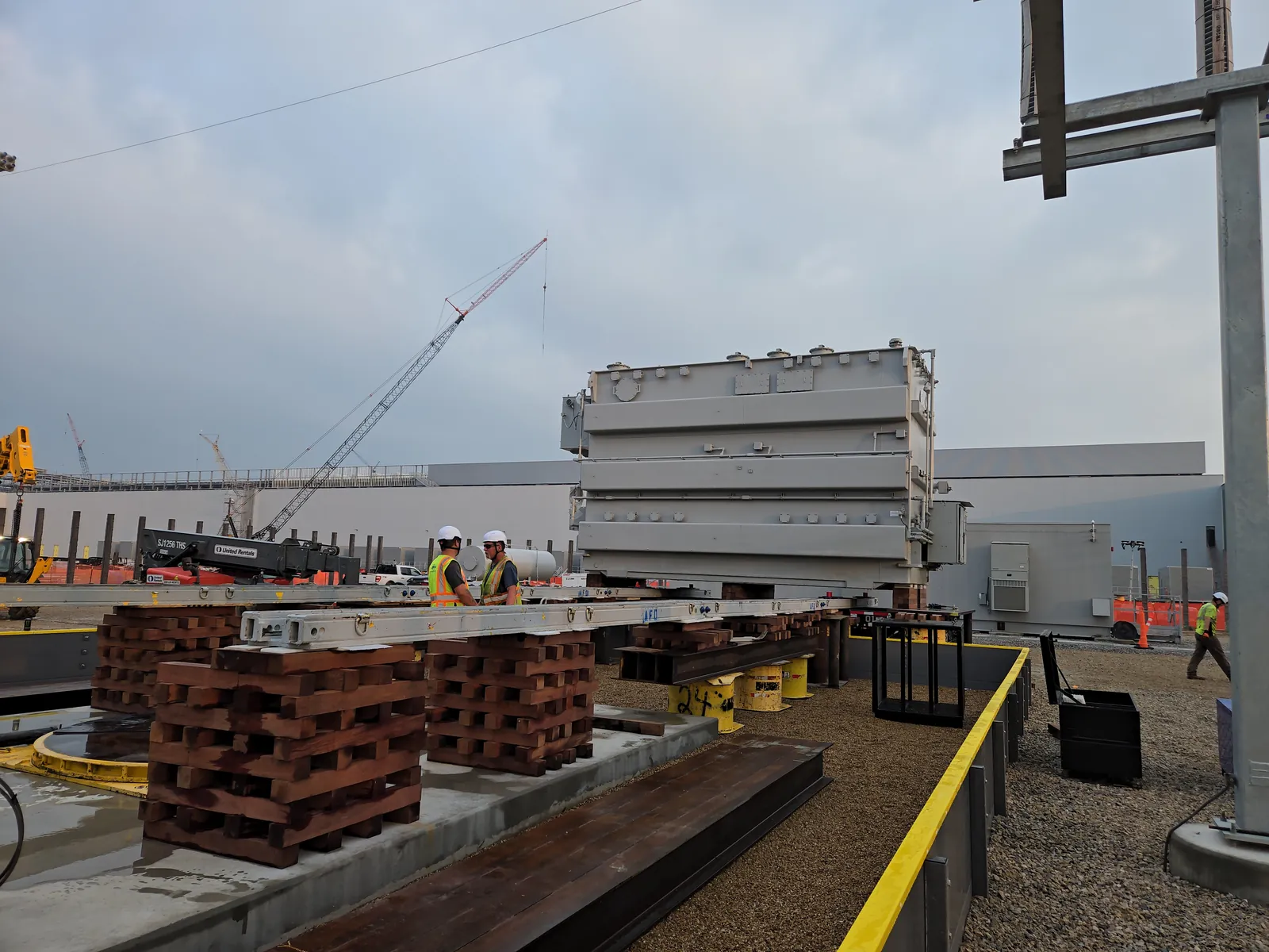 Transformer raised on timber cribbing beside steel slide rails for a jack and slide set