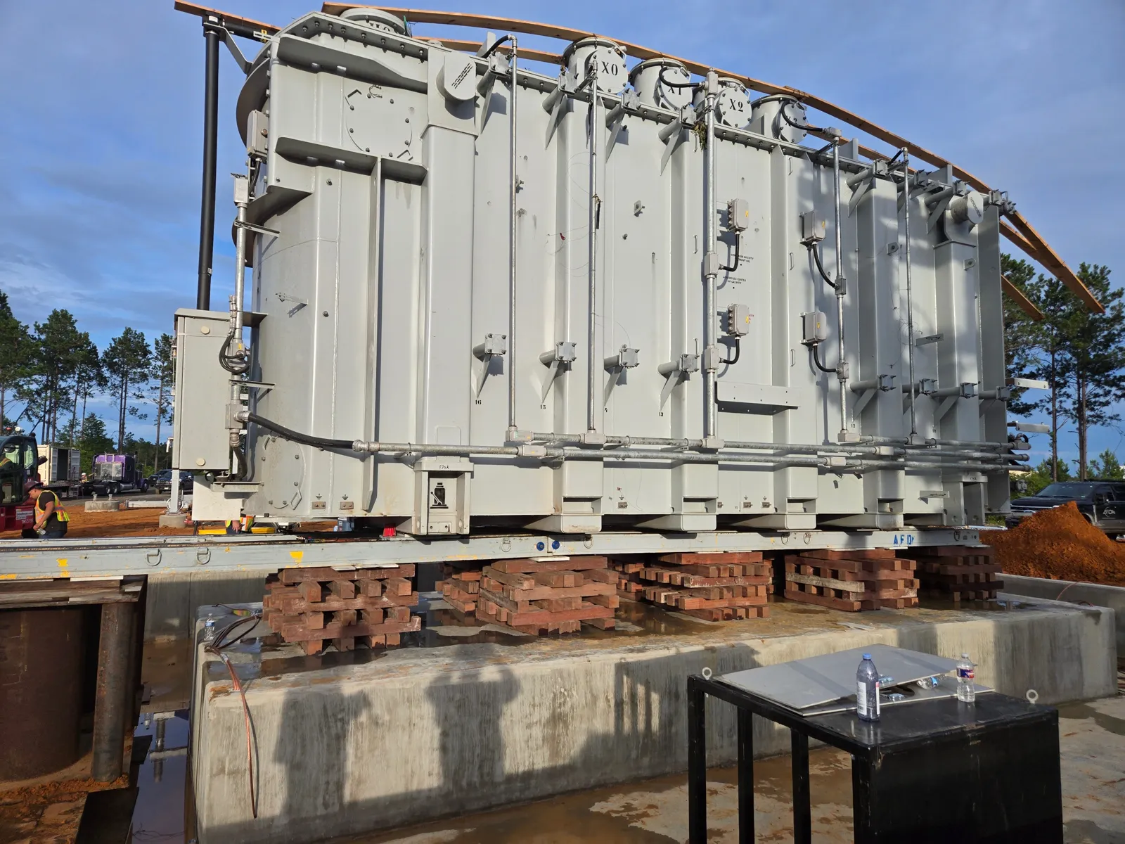 Transformer lifted on timber cribbing above its concrete foundation